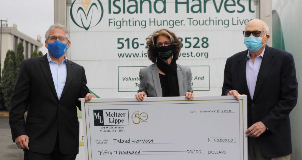 Meltzer Lippe managing partner David Heymann and Chairman Lew Meltzer present a $50,000 donation to Island Harvest President and CEO Randi Shubin-Dresner. / Courtesy of Meltzer Lippe